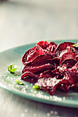 Beet chips with basil and sea salt, on blue plate