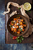 Roasted sweet potato in a bowl topped with chilli, coriander and feta cheese