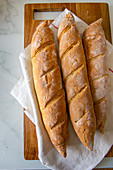 Three baguettes on a wooden chopping board