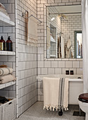 White tiles and bathtub below large mirror in bathroom