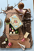 Vintage-style Easter arrangement with tin in wire basket on cardboard