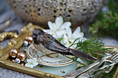 Bird ornament and vintage-style cutlery on gilt tray