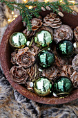 Green baubles and larch cones in bowl