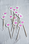 Toothpicks decorated with circles of book pages and pink paper hearts