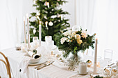 Flowers and gifts on table set for Christmas in shades of cream