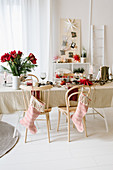 Weihnachtstisch mit rotem Amaryllisstrauß, Stühle mit Weihnachtsstrumpf