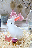 Weiße Hasenfigur im Nest aus Holzwolle als Osterdeko