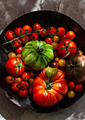 Various types of tomatoes in an antique colander