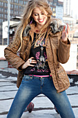 Junge blonde Frau in Winterjacke, Motivpulli und Jeans
