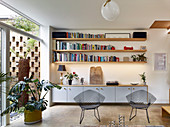 Floating sideboard and shelves next to glass wall overlooking courtyard garden