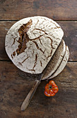 A loaf of fresh country bread, sliced on a wooden surface