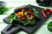 Vegan black burger with mock duck, Asian salad and grilled vegetables