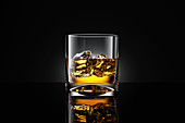 Ein Glas Whiskey mit Eis vor schwarzem Hintergrund