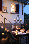 Table and chairs with tealights and candle chandelier on twilight terrace