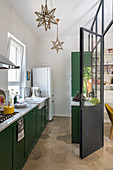 Narrow kitchen with dark green cabinets and honeycomb floor tiles