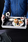 Blinis mit Kaviar und saurer Sahne serviert auf Tablett