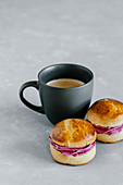 Cup of coffee and brioche buns with blackcurrant cream