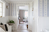 Vorraum mit weißer, halbhoher Holzverkleidung und romantischer Tapete