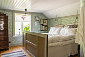 Bed made from reclaimed materials in bedroom with patterned wallpaper