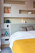 Double bed surrounded by modular shelving in bedroom