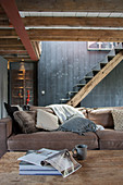 Rustic living room in shades of grey and brown with metal stairs on wooden beam