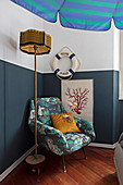 Armchair and maritime accessories on and against wall with blue painted dado