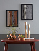 Artworks made from wooden veneers on grey wall and sculptural vases on table