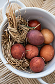 Easter eggs coloured using natural dyes in straw nest