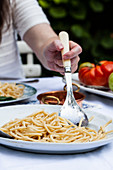 A platter of pasta cacio e pepe being served (pasta with cheese and pepper) an an outdoor table