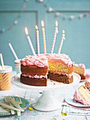 Geburtstagstorte mit rosa Frosting dekoriert mit brennenden Kerzen