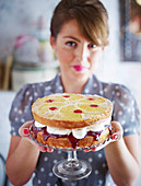 Frau präsentiert Upside-Down-Sandwichkuchen mit Ananas und Kirschen