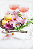 Different colored macarons decorated with flowers on a silver plate