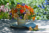 Strauß aus Kapuzinerkresse, Glockenblumen und Wiesenkümmel in Kaffeebecher