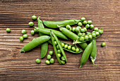 Fresh pea pods on a wooden surface