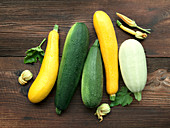 Various fresh yellow, green and white zucchini on a wooden background