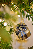 Gift-shaped Christmas bauble hanging from branch