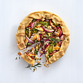 Onion tart with peaches, rosemary, goat's cheese and pistachio nuts