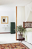 View of bed with DIY bed head made from collected branches and bathroom ensuite