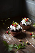 Two chocolate cupcakes with wild strawberries and whipped cream
