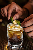 Barkeeper garniert Cocktail mit Limettenschale in einer Bar
