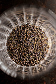 Heap of dried aromatic lavender seeds placed inside glass cup on table in kitchen