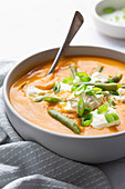 Bowl of pumpkin soup with green beans, sour cream and sliced spring onions