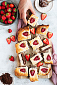 A hand grabbing coconut ice with a chocolaty bottom and strawberry topping sliced