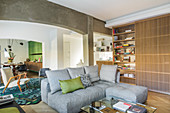 Grey sofa set next to oak bookcase in open-plan interior