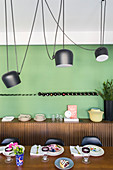 Elegant walnut table, pendant lamps and sideboard in dining room with green accent wall