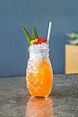 Cocktail mit Eis und Strohhalm in einem Glas in Ananasform
