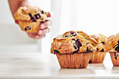 Rustic blueberry muffins on a white, wood table