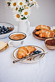 Croissants mit Blaubeeren und einer Tasse Kaffee auf Frühstückstisch