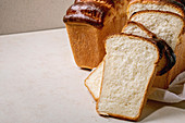 Homemade Hokkaido wheat toast bread whole and sliced on white cloth on table