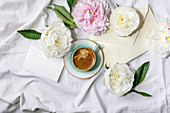 Cup of espresso coffee, blank paper, envelope, pink and white peonies flowers with leaves